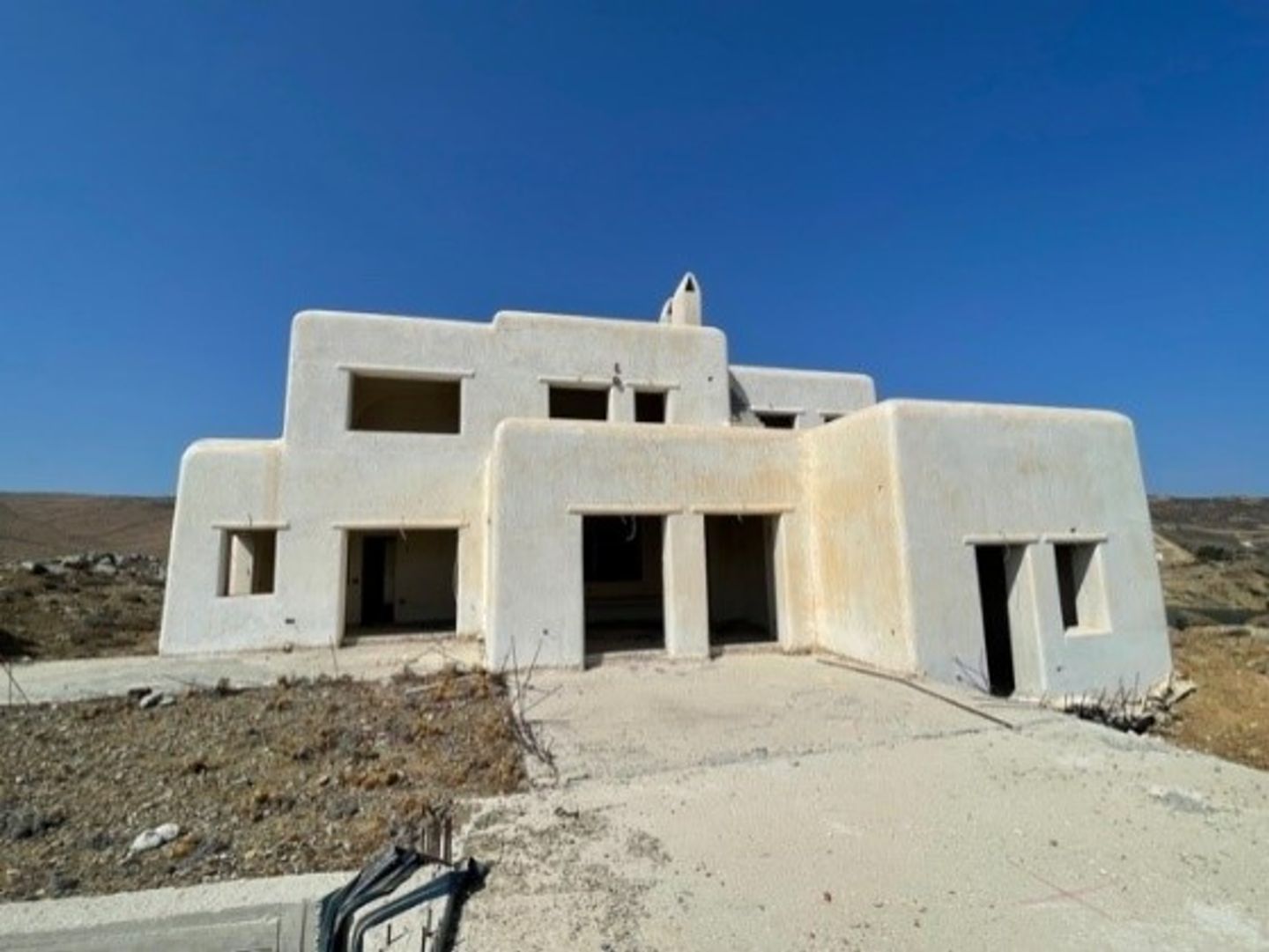 Foto von einer Anlage mit mehreren nicht zu Ende gebauten Villen auf Mykonos, die von EOS unter nachhaltigen Aspekten saniert werden.