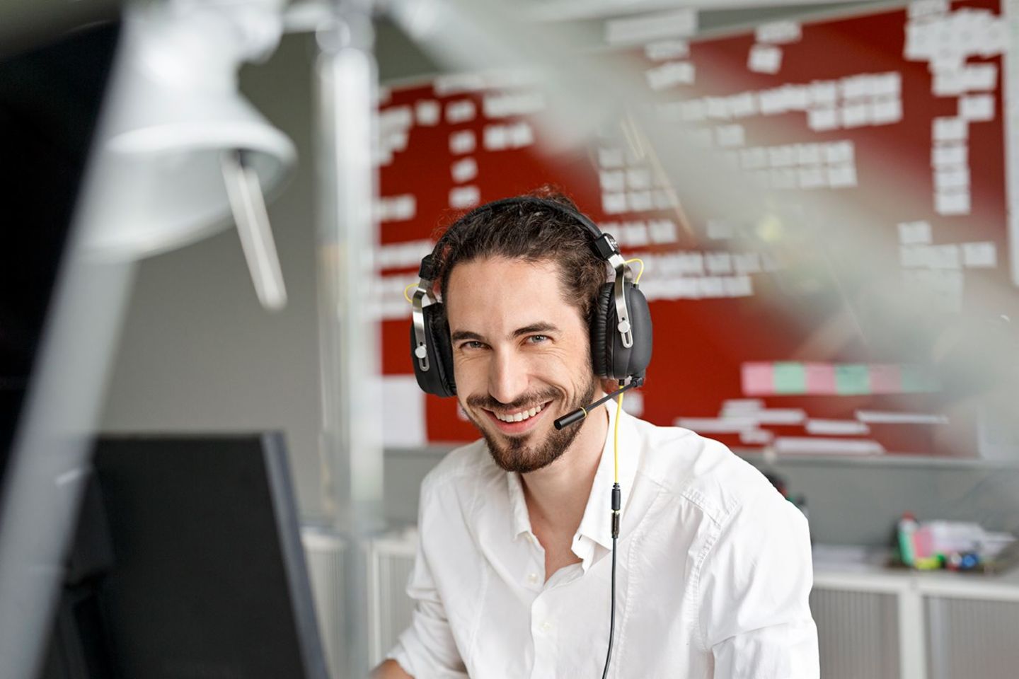 Künstliche Intelligenz im Callcenter: Callcenter-Mitarbeiter sitzt lachend am Arbeitsplatz.