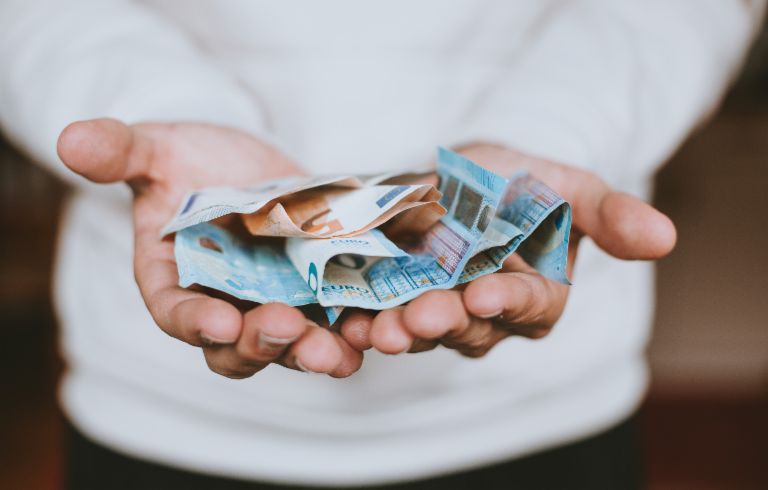 Ist Bargeld weiter König? Mann hält Euroscheine in beiden Händen 