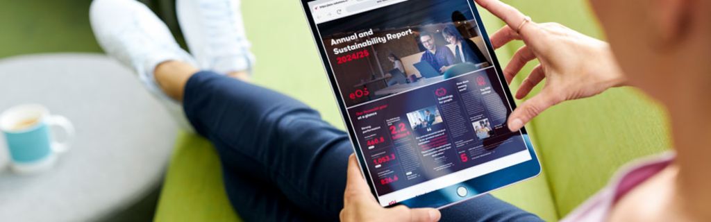 Personne sur un canapé vert consultant le Rapport Annuel et de Durabilité EOS 2024/25 sur une tablette