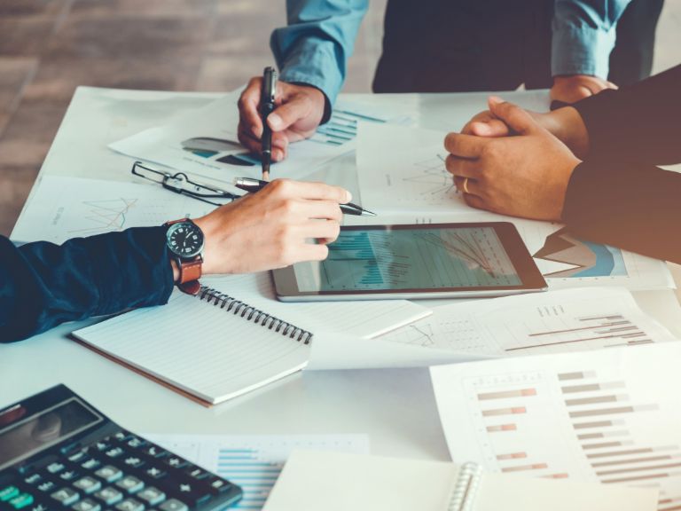 Robotic Process Automation: Menschen an einem Schreibtisch mit Unterlagen.