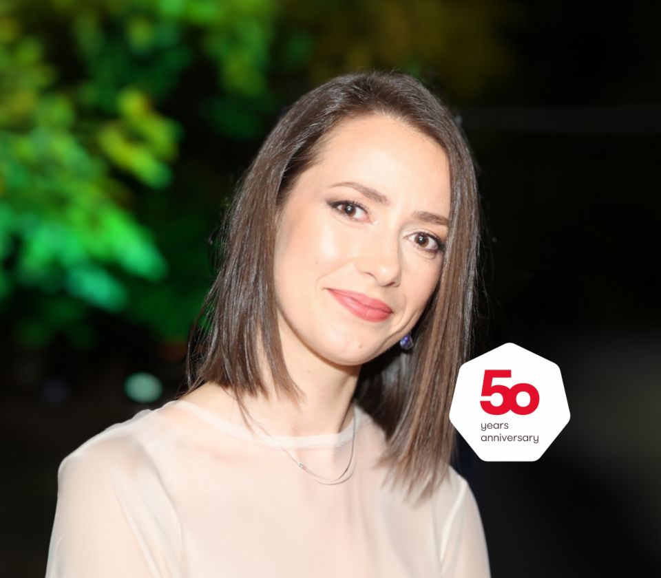 Dilyana Taneva Manager Corporate & International Collection, EOS Bulgarien, in einem hellen Oberteil vor dunklem Hintergrund