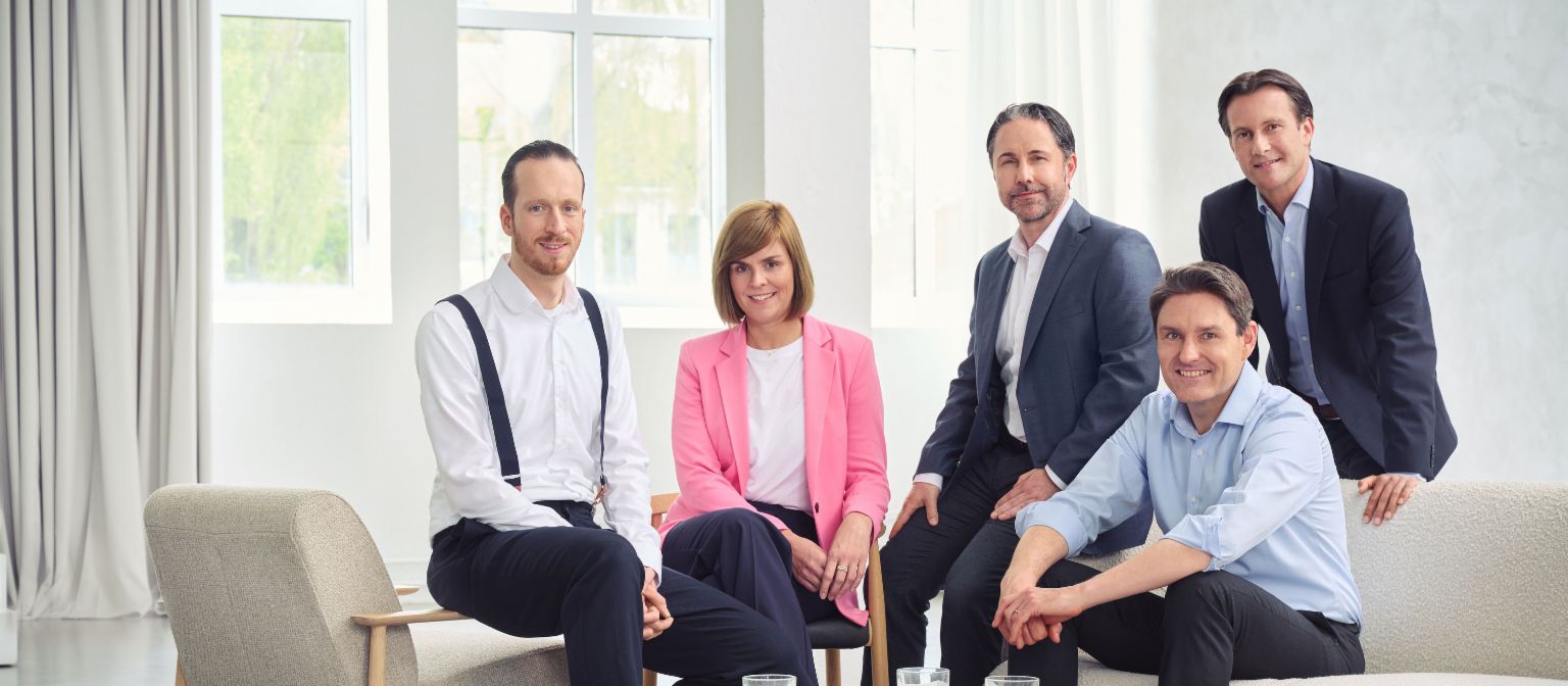 EOS Group Board of Directors (von links nach rechts: Sebastian Pollmer, Dr. Eva Griewel, Marwin Ramcke, Dr. Stephan Ohlmeyer, Carsten Tidow), in einem hellen Raum mit direktem Blick in die Kamera