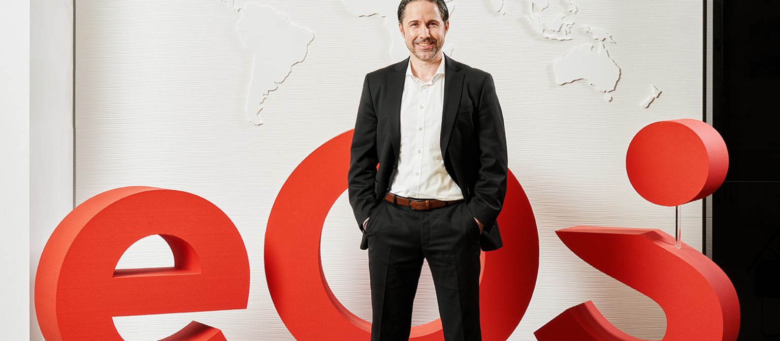 Marwin Ramcke, CEO of the EOS Group, stands in front of a large 3D model of the red company logo