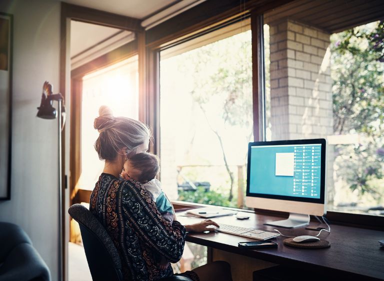 Eine Mutter sitzt mit ihrem Baby zuhause vor dem Computer. Einkommensabhängige Kredite: Eine Mutter sitzt mit ihrem Baby zuhause vor dem Computer.
