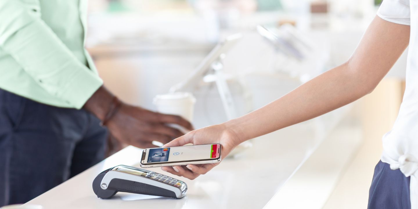 Mobile Payment: Frau bezahlt im Laden per Smartphone.