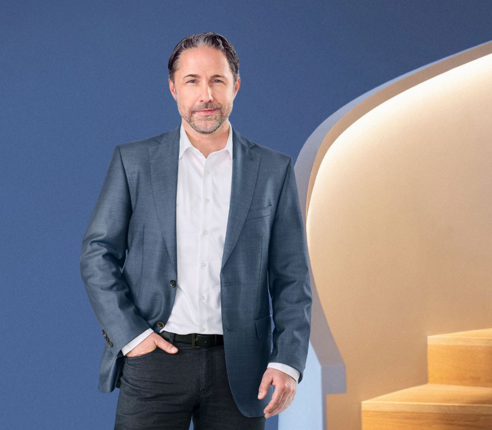 Marwin Ramcke, directeur Général du groupe EOS, se tient devant un fond bleu, vêtu d'une veste sombre. Il regarde directement vers la caméra.