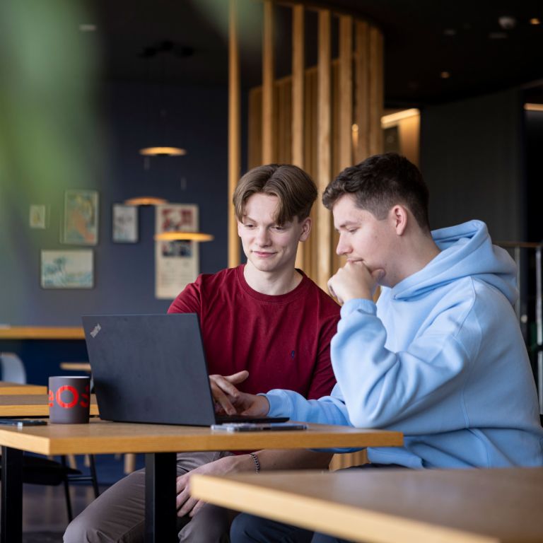 Deux jeunes collaborateurs d'EOS examinent ensemble un écran d'ordinateur et discutent de ce qu'ils voient.