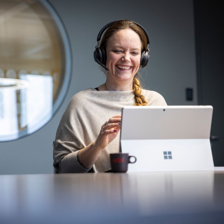 Un employé d'EOS porte un casque et sourit en conversant avec un interlocuteur numérique.
