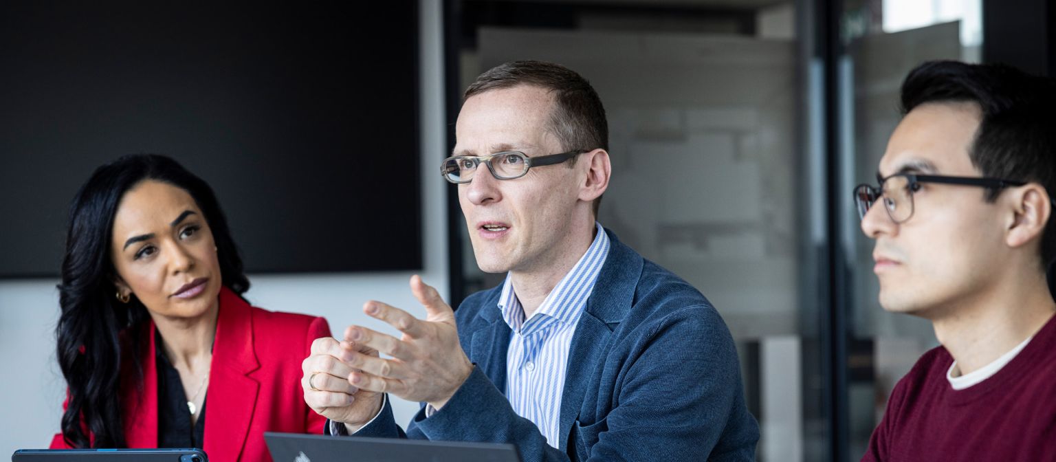 Trois personnes ont une conversation dans un bureau.